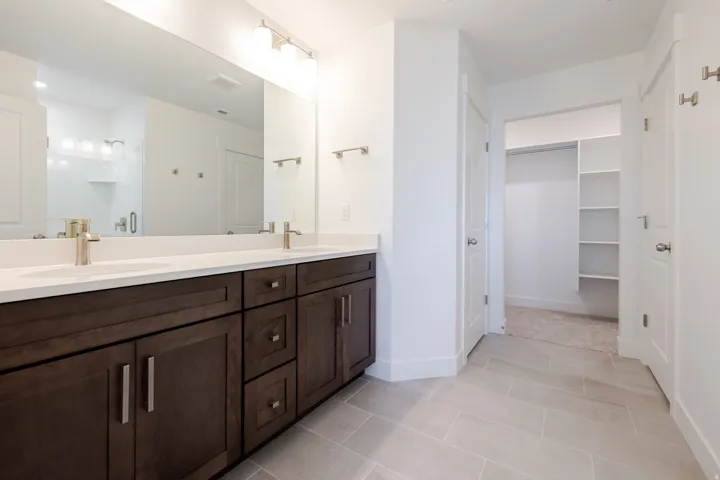 Full bath with double vanity, a stall shower, and a spacious closet
