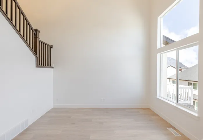 Empty room with light wood-style flooring and a high ceiling