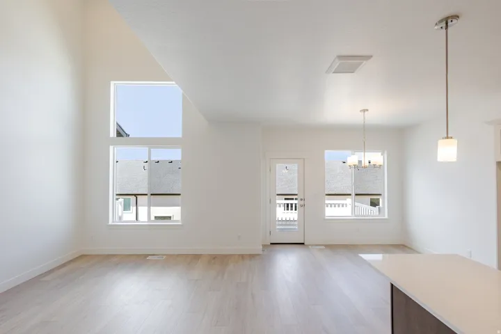 Unfurnished dining area with a chandelier, light wood finished floors, and a high ceiling