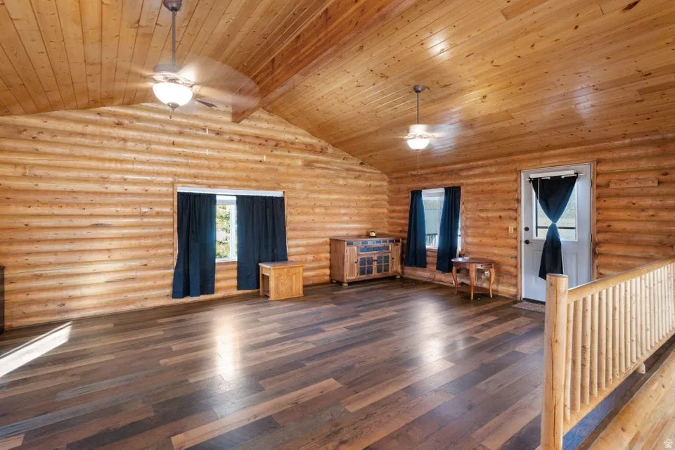 Unfurnished living room with hardwood / wood-style flooring, ceiling fan, log walls, and wood ceiling