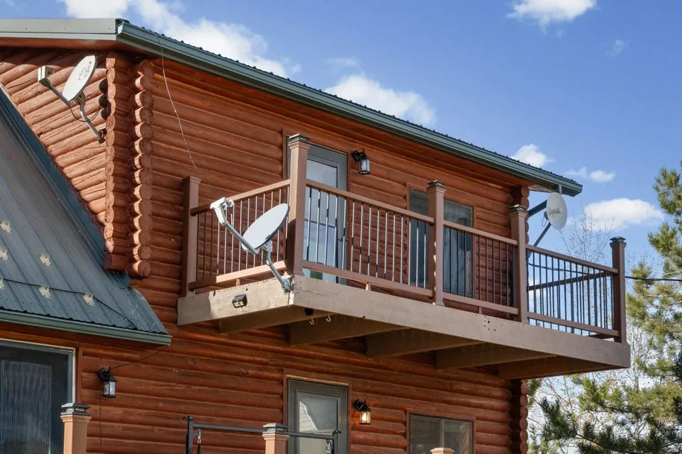 View of side of home with log siding, a balcony, and a metal roof
