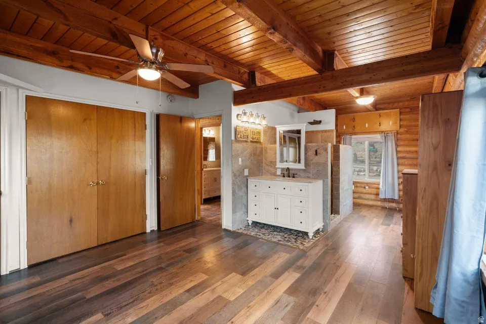 Unfurnished bedroom with dark wood-style floors and a wood ceiling with exposed beams