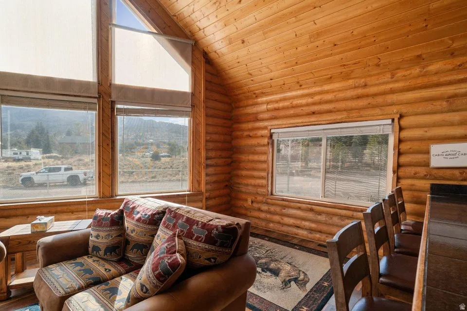 Living room with wooden ceiling, high vaulted ceiling, and rustic walls
