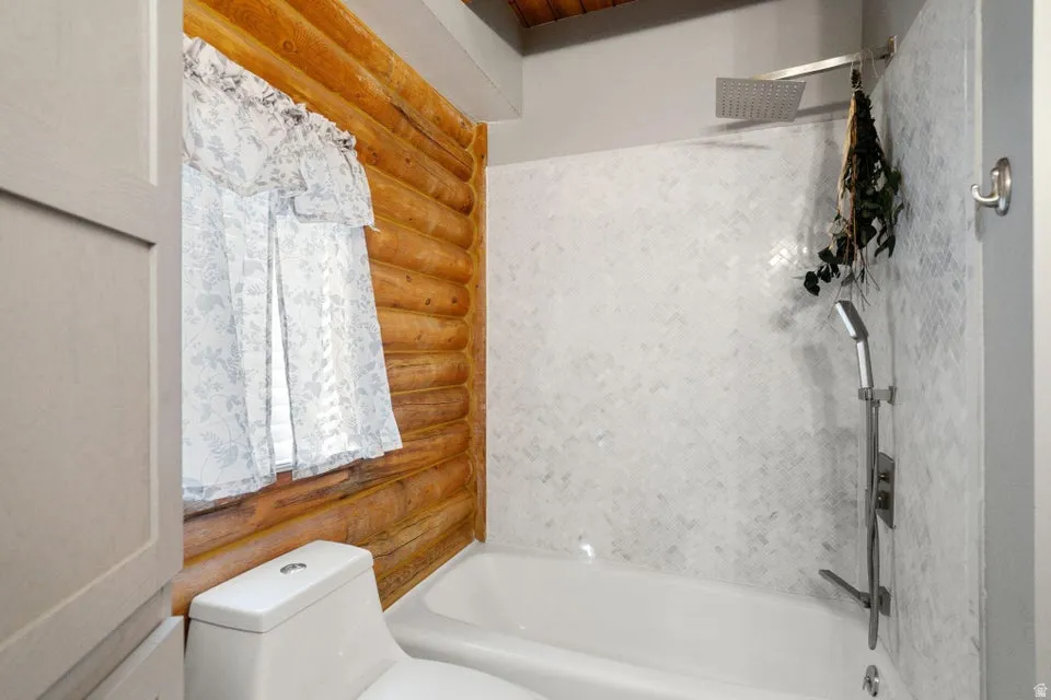 Full bathroom with rustic walls and shower / bathtub combination