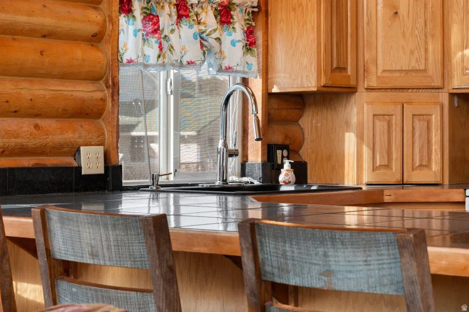 Kitchen featuring rustic walls and tile countertops