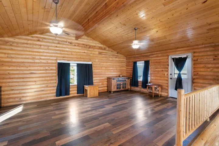 Unfurnished living room with hardwood / wood-style flooring, ceiling fan, log walls, and wood ceiling
