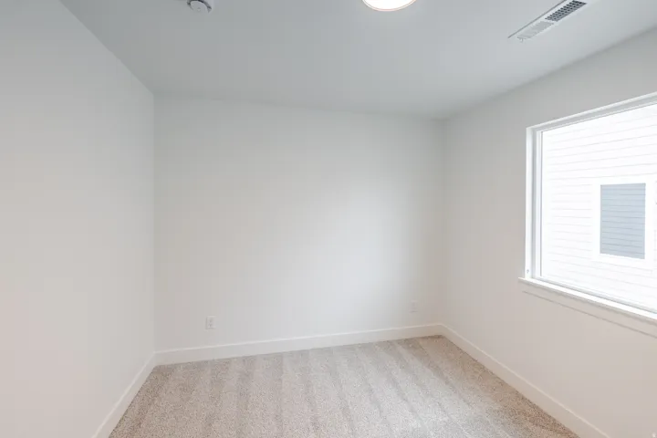 Empty room featuring light colored carpet and baseboards
