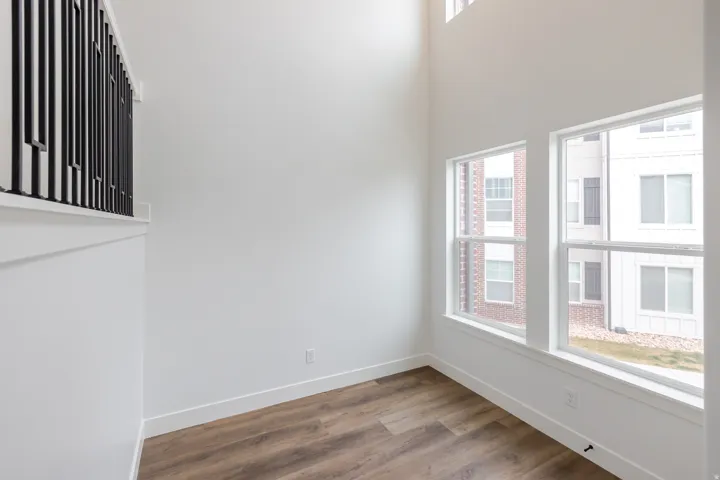 Empty room with dark wood-type flooring and a high ceiling