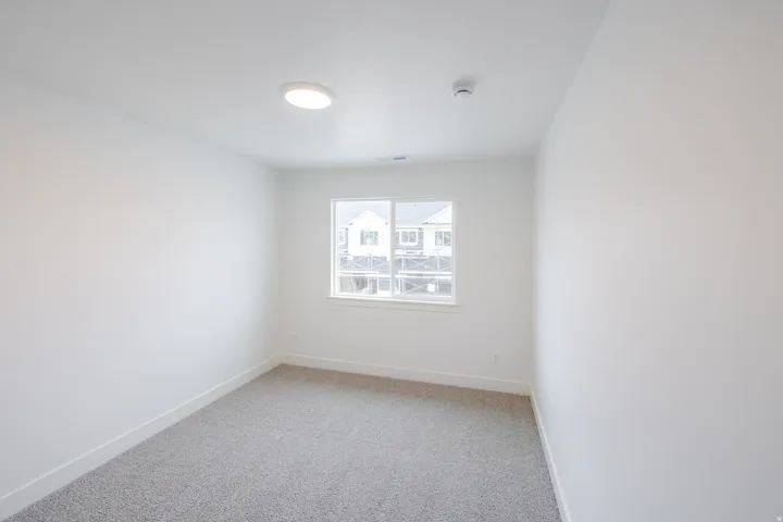 Empty room featuring light colored carpet and baseboards