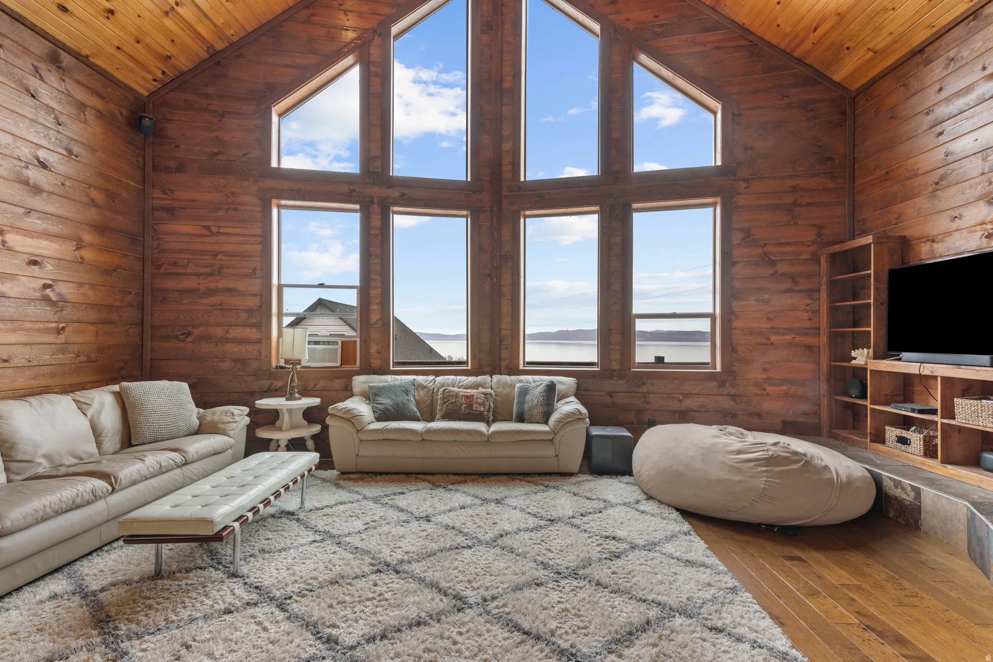 Living room with wood walls, high vaulted ceiling, hardwood / wood-style floors, and wood ceiling