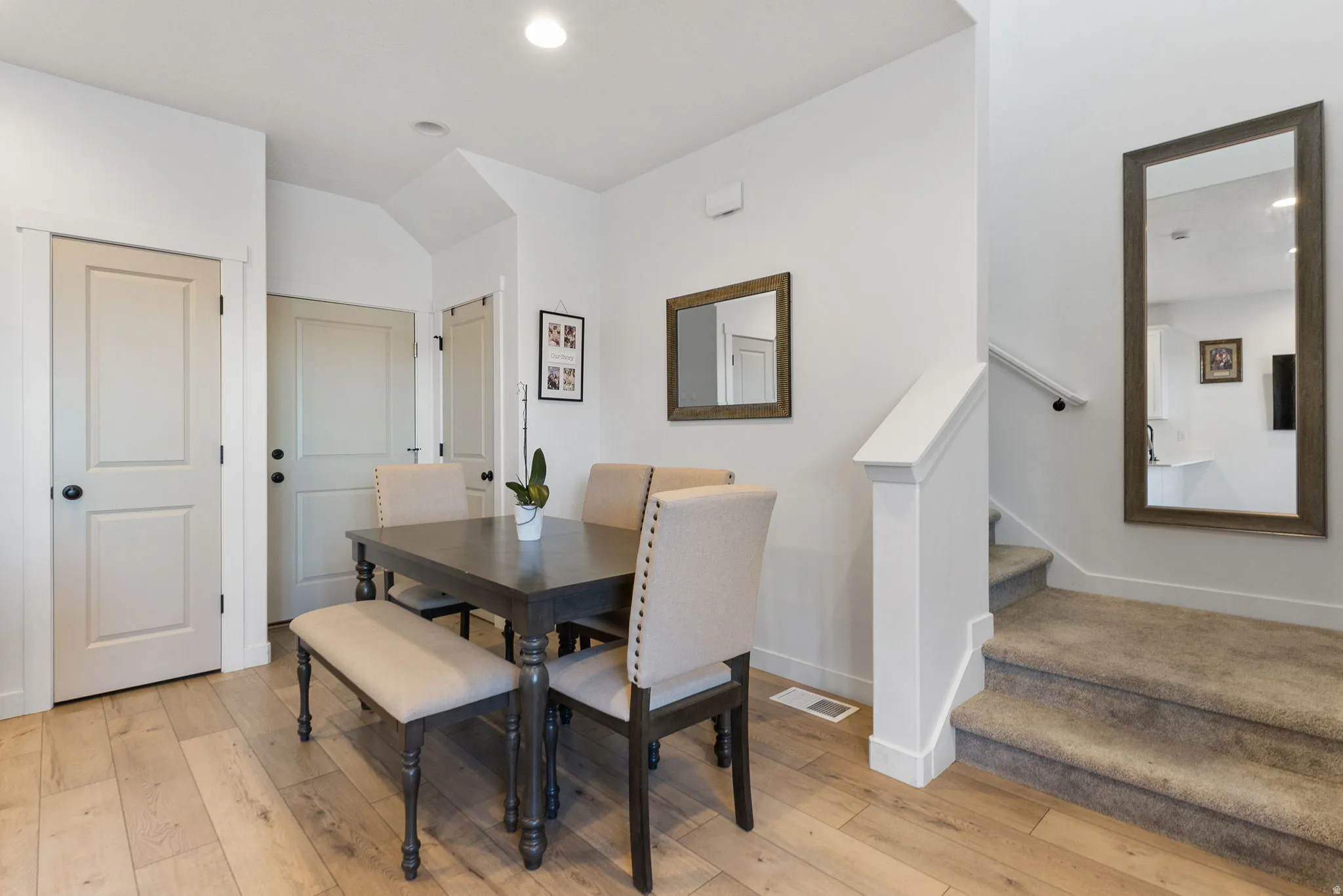 Dining room with light wood finished floors, stairs, recessed lighting, and lofted ceiling