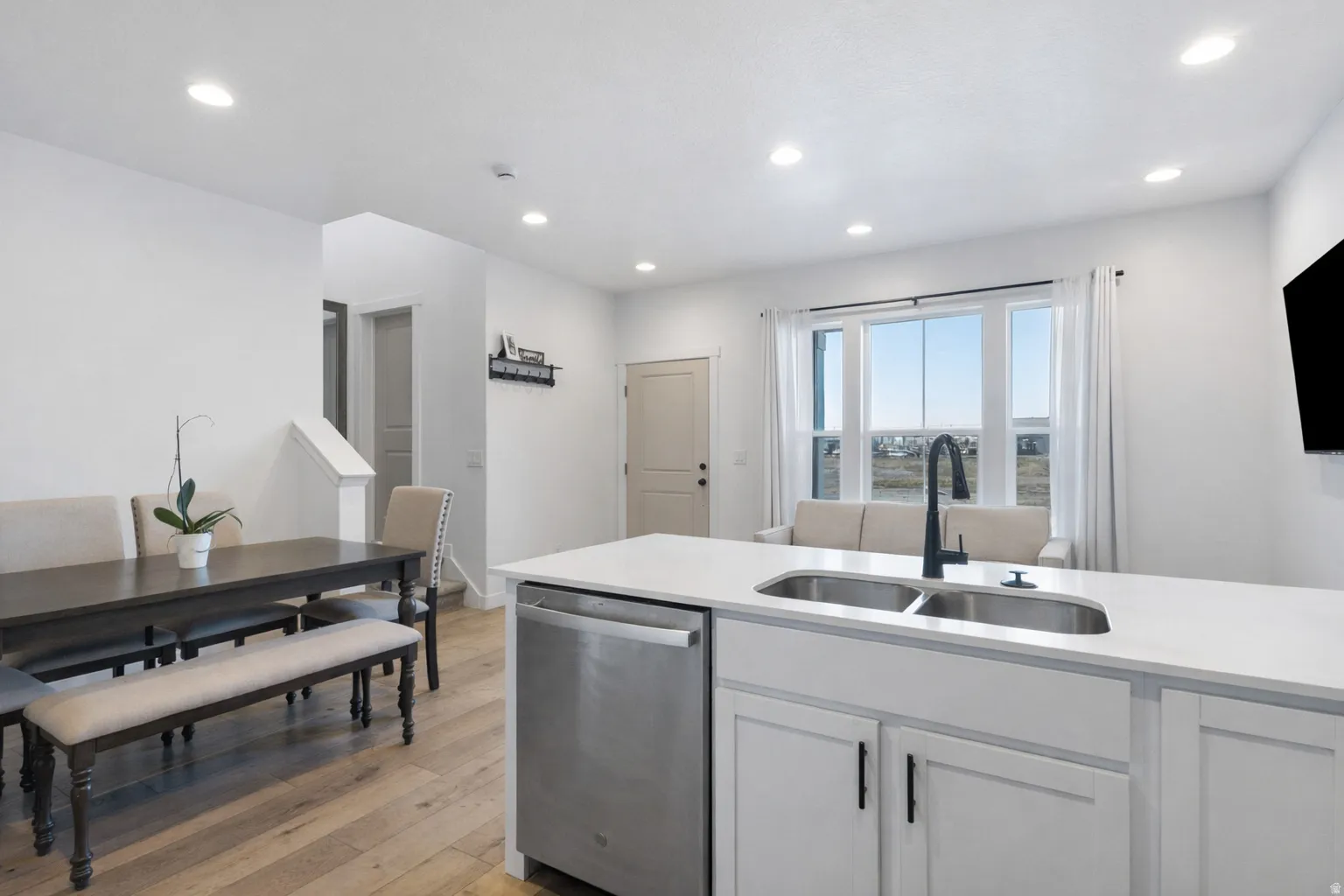 Kitchen with dishwasher, light wood-style floors, white cabinets, recessed lighting, and light stone counters