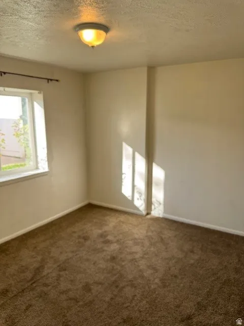 Spare room with a textured ceiling and dark carpet