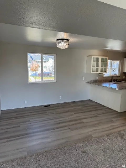 Unfurnished dining area featuring a textured ceiling, dark wood-style flooring, and a chandelier