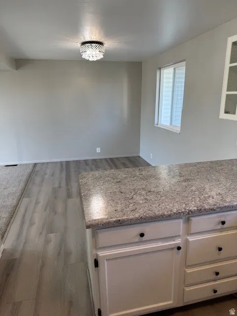 Kitchen with white cabinets, light stone countertops, and light wood-type flooring