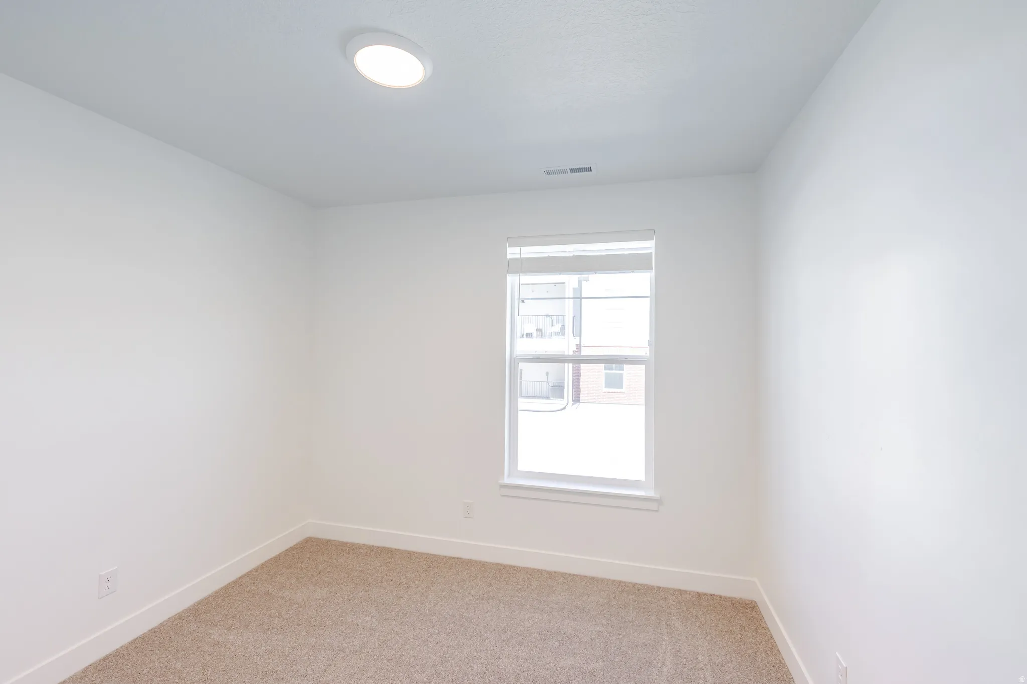Empty room featuring baseboards and light carpet