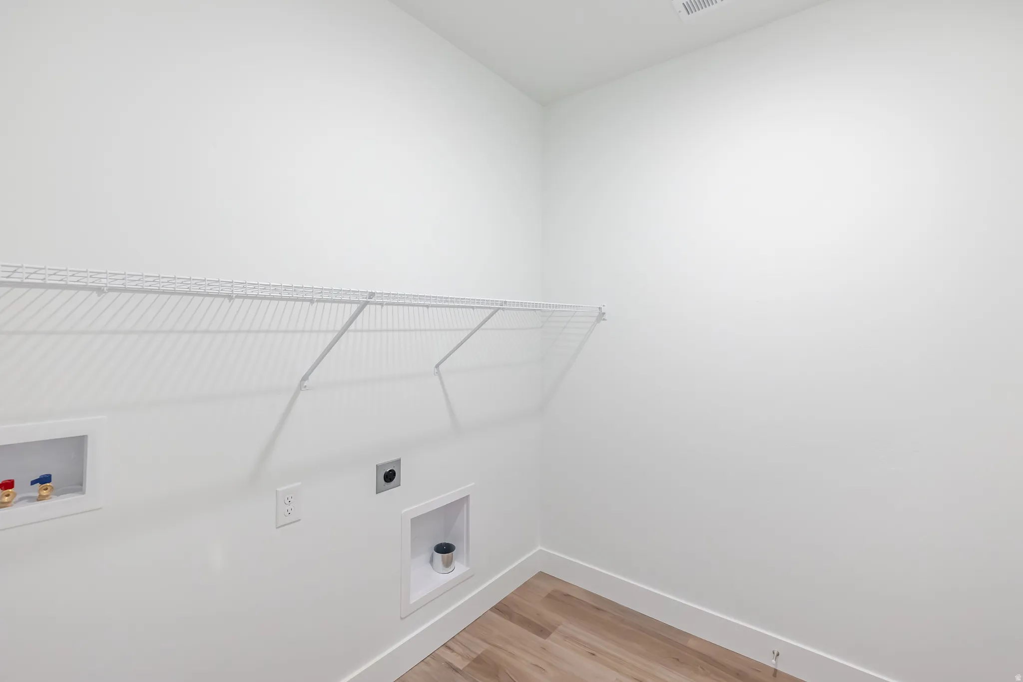 Laundry area with hookup for a washing machine, light wood-style flooring, and hookup for an electric dryer