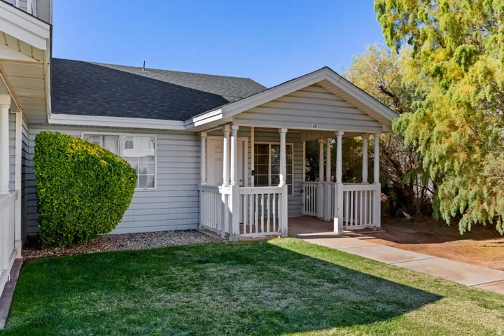 View of front of property with a shingled roof, a front yard, and covered porch