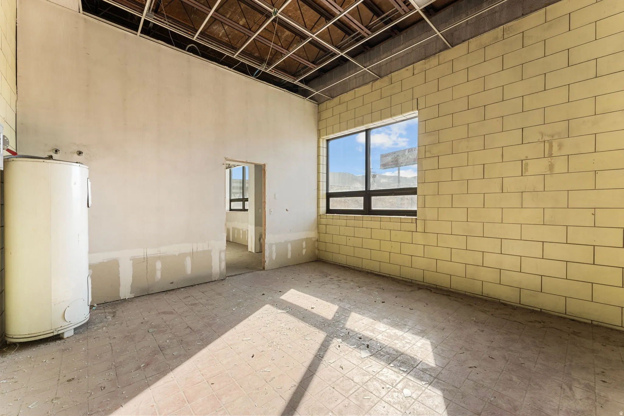 Unfurnished room featuring water heater and a towering ceiling