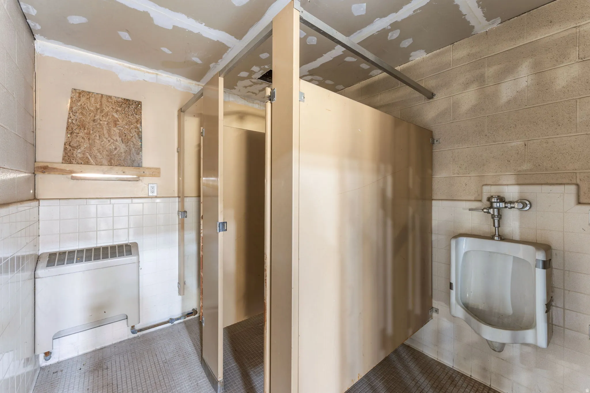 Bathroom featuring tile walls, tile patterned flooring, heating unit, and a stall shower