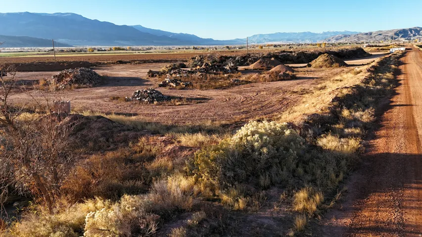 Expansive undeveloped land featuring a dirt road, natural vegetation, and distant mountain backdrop