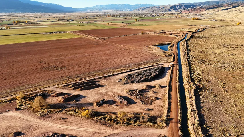 Expansive acreage featuring cultivated fields, natural terrain, a water canal, and a small pond