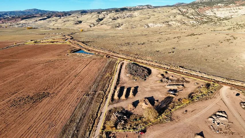Expansive undeveloped land featuring a natural pond, visible railroad tracks, and distant mountainous terrain