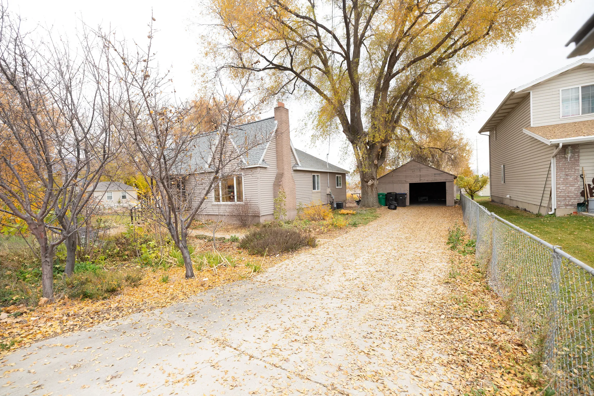 View of home's exterior with a detached garage, an outdoor structure, a chimney, and driveway