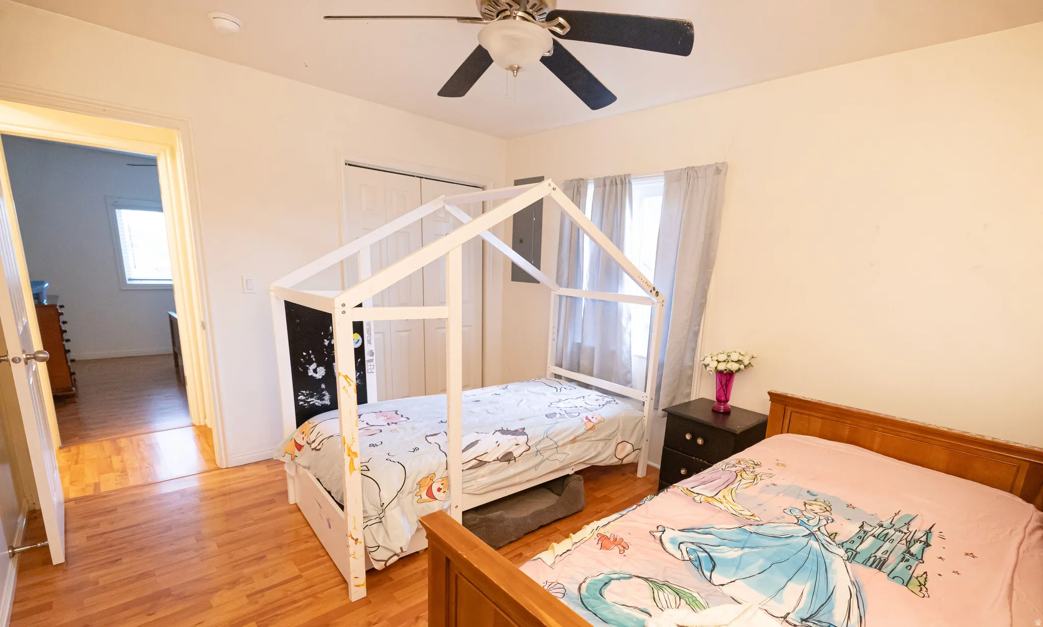 Bedroom featuring light wood-type flooring, multiple windows, ceiling fan, and a closet
