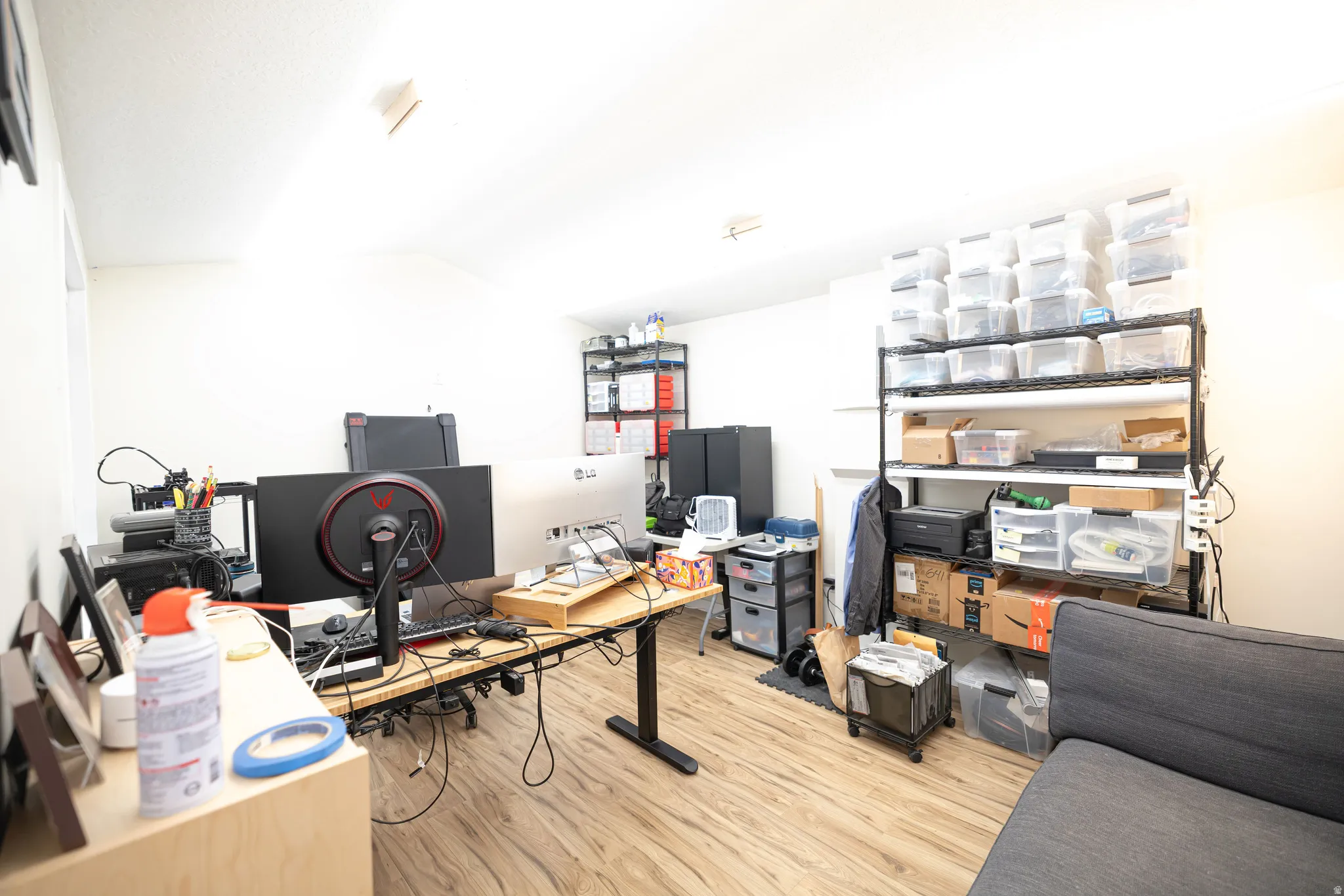 Home office with light wood-style flooring and vaulted ceiling