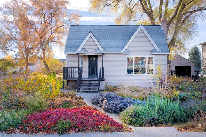 View of front facade featuring a shingled roof, a chimney, and an outdoor structure