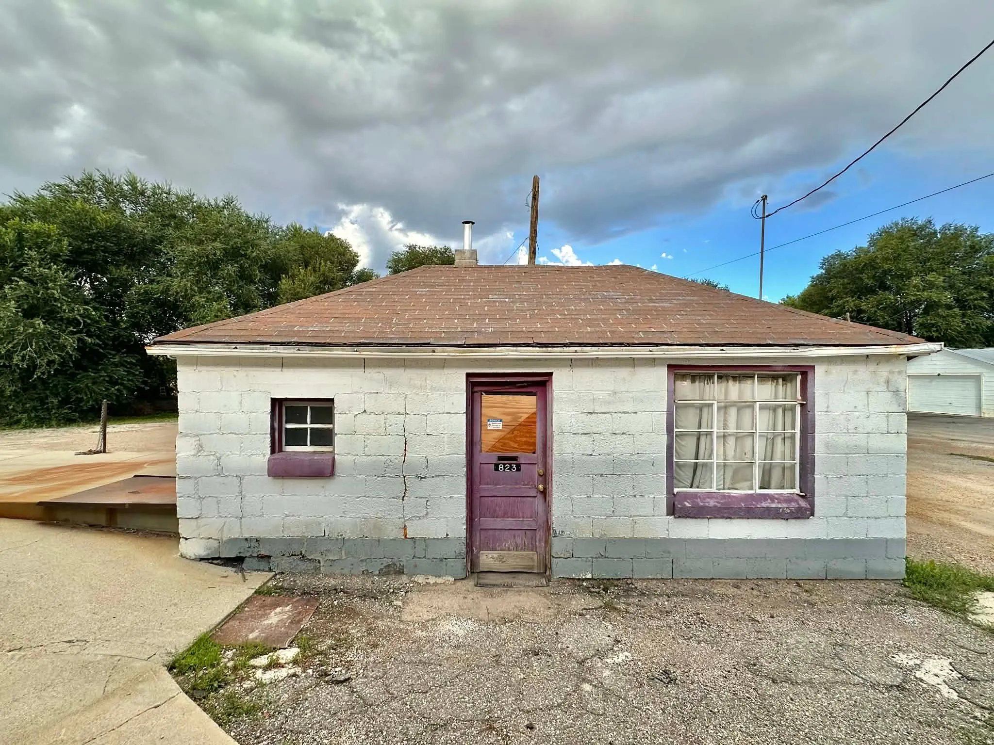 View of front of property featuring concrete block siding and a shingled roof