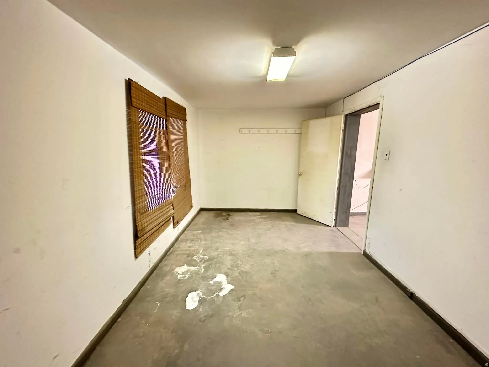 Unfurnished bedroom with concrete floors and baseboards