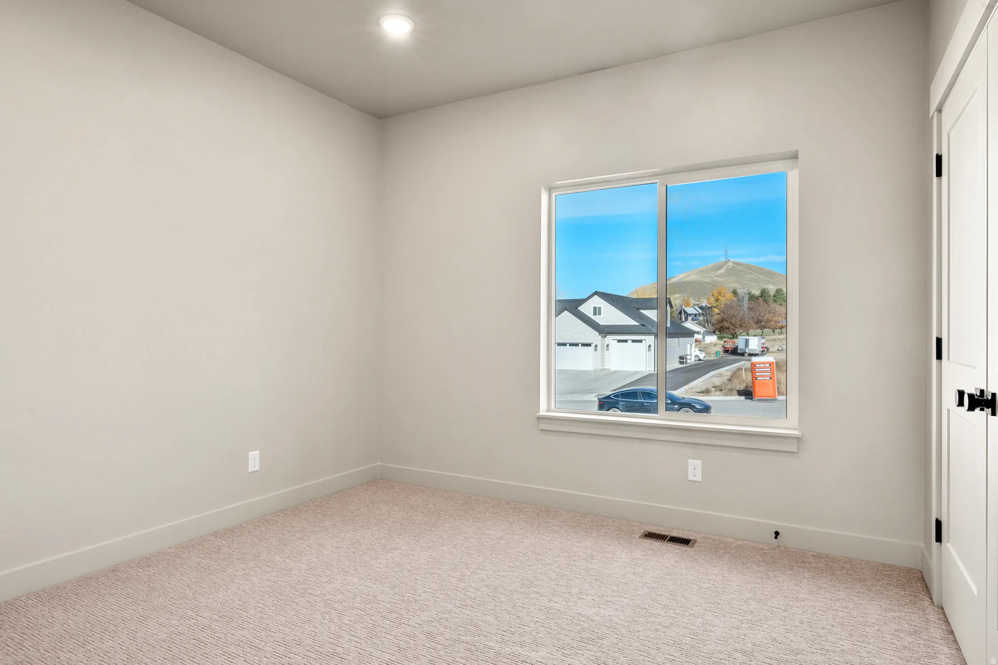 Carpeted empty room with recessed lighting and a residential view