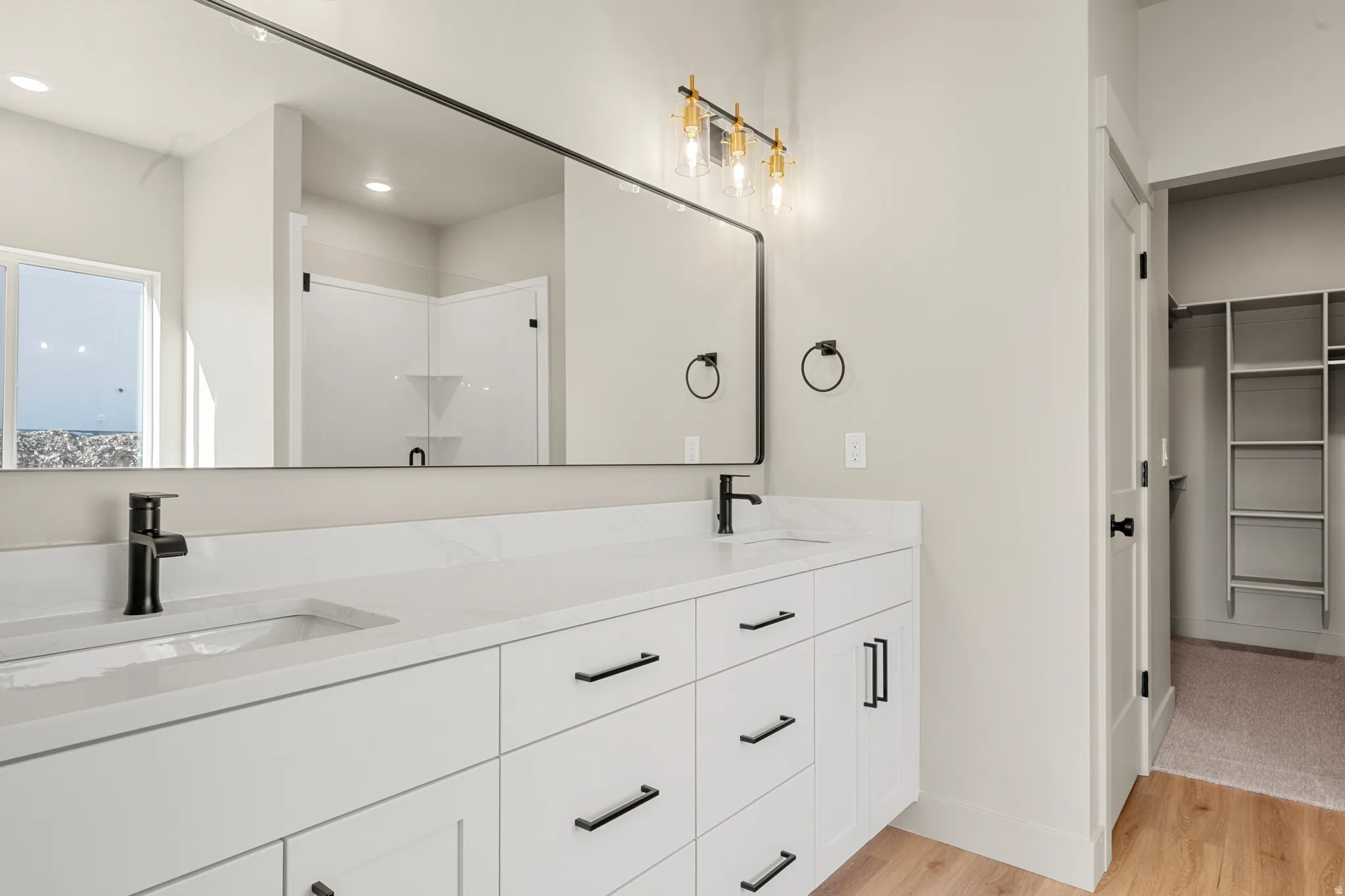 Full bath with light wood-type flooring, a stall shower, double vanity, a spacious closet, and recessed lighting