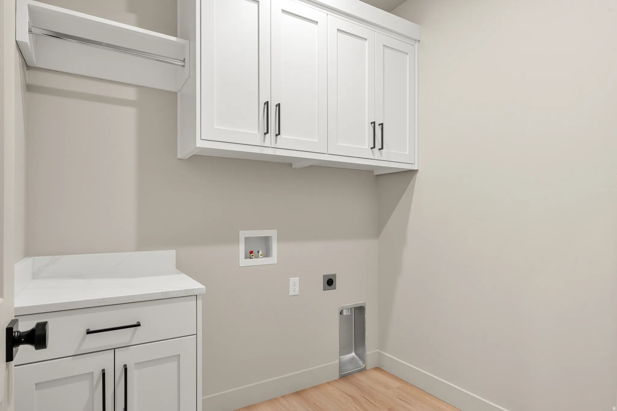 Laundry area featuring light wood finished floors, hookup for a washing machine, cabinet space, and hookup for an electric dryer