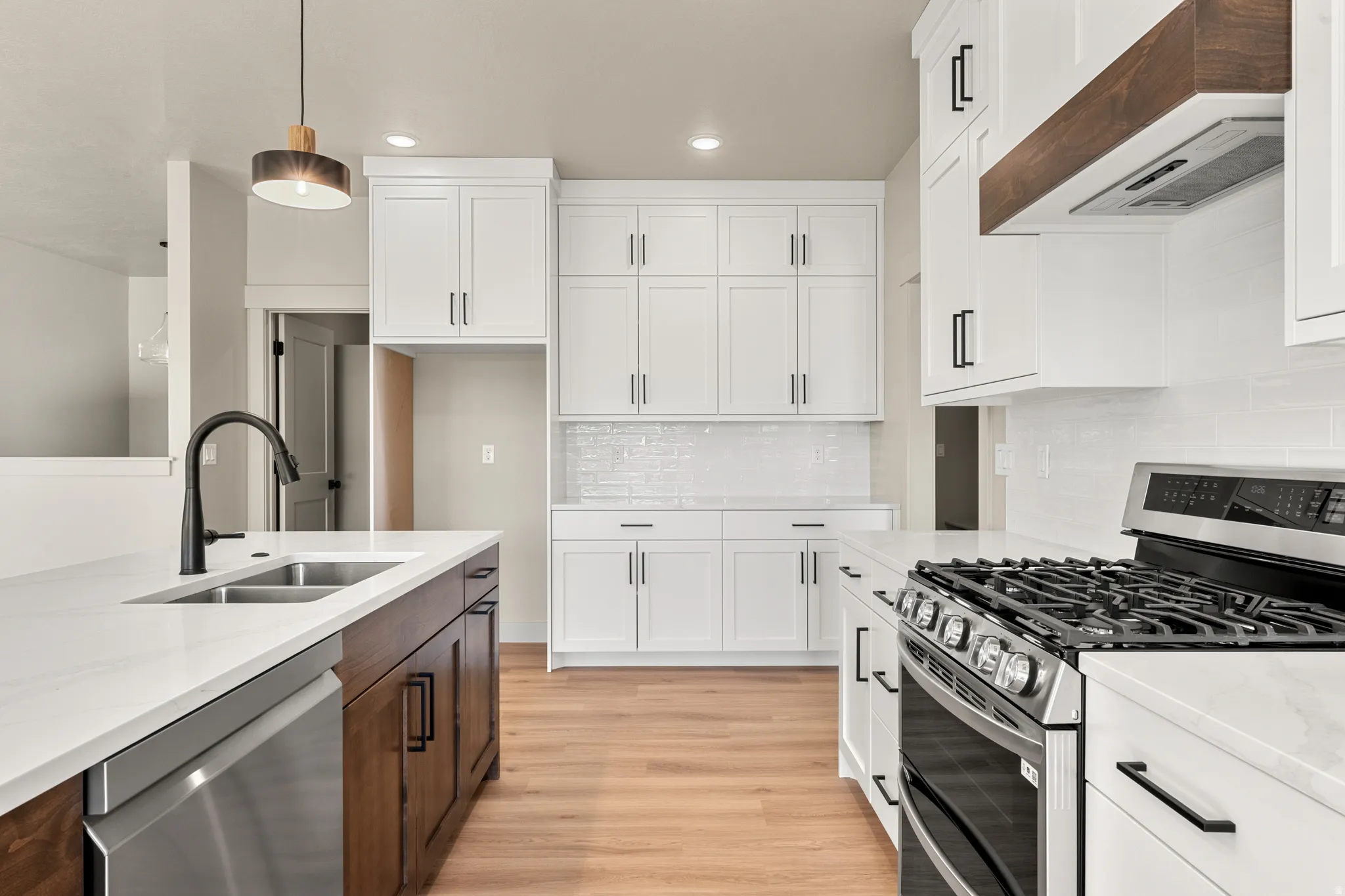 Kitchen with appliances with stainless steel finishes, white cabinets, light stone counters, custom exhaust hood, and recessed lighting