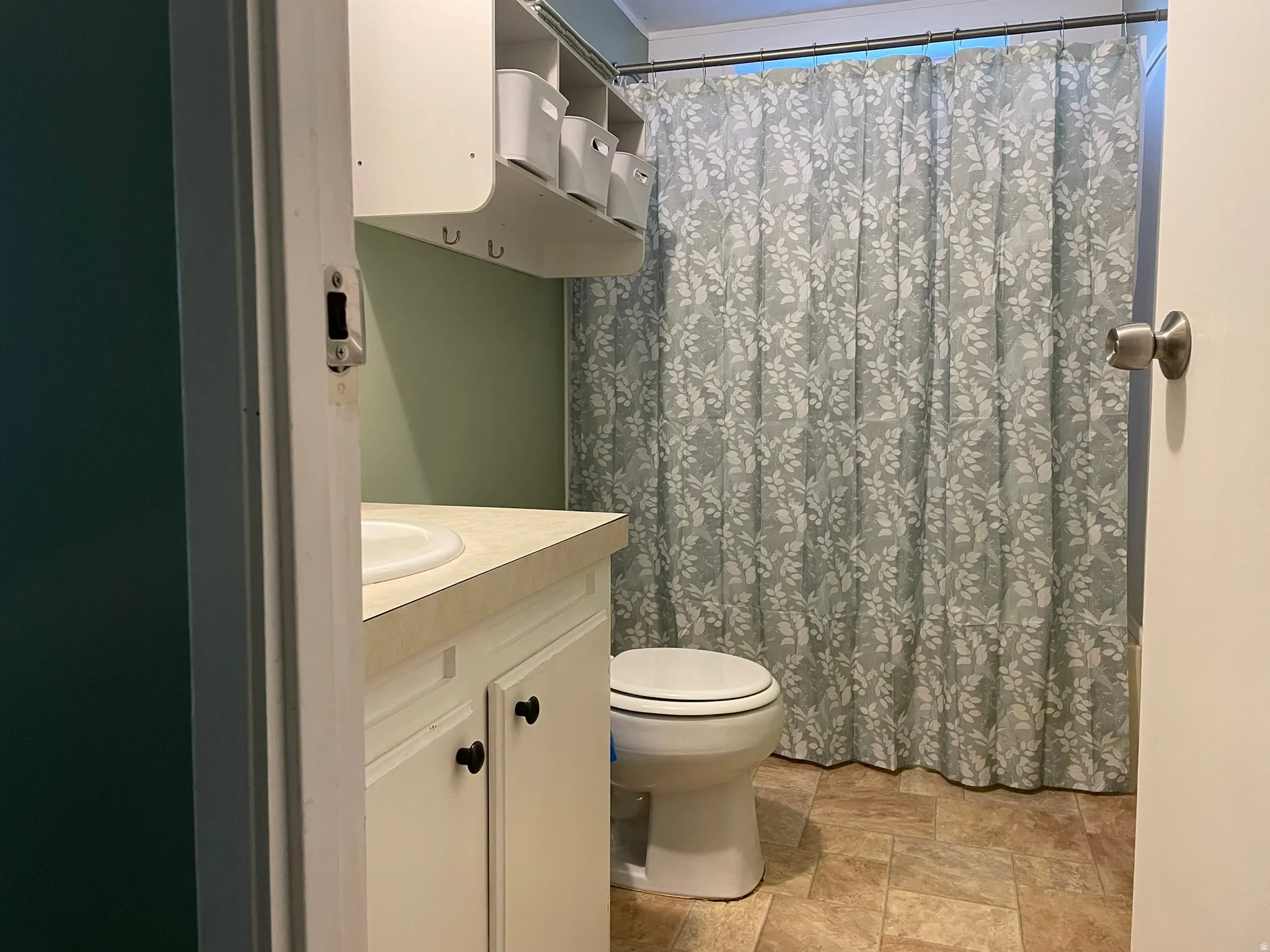 Bathroom featuring vanity, curtained shower, and stone finish flooring