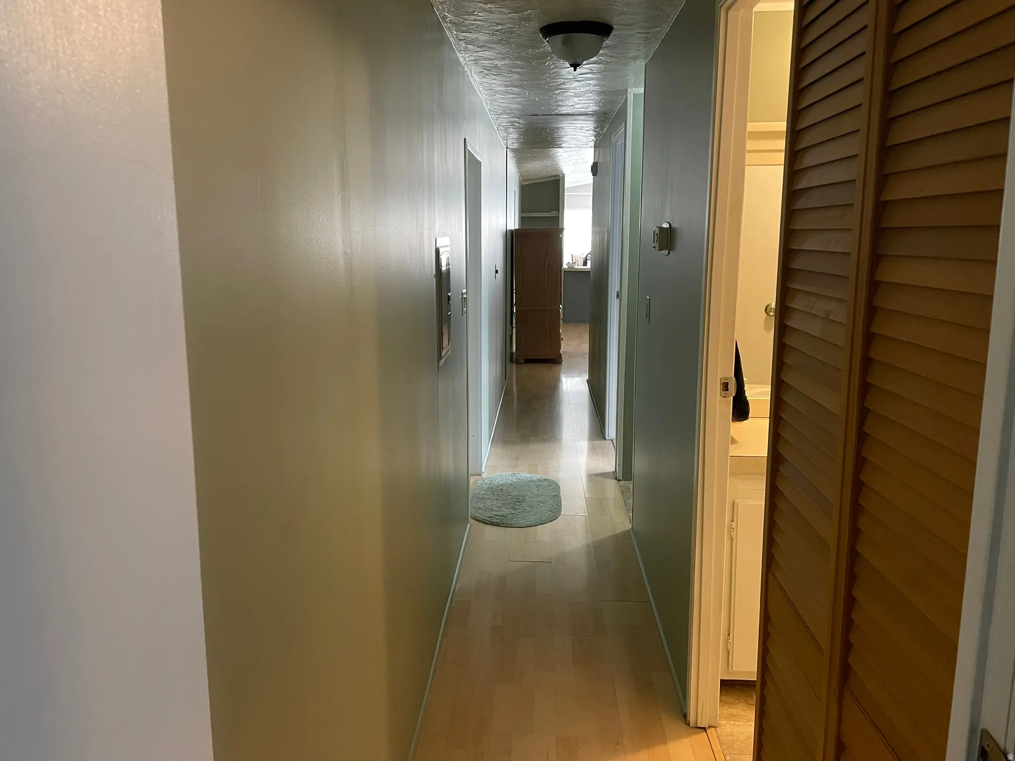 Hallway featuring light wood-style floors and a textured ceiling