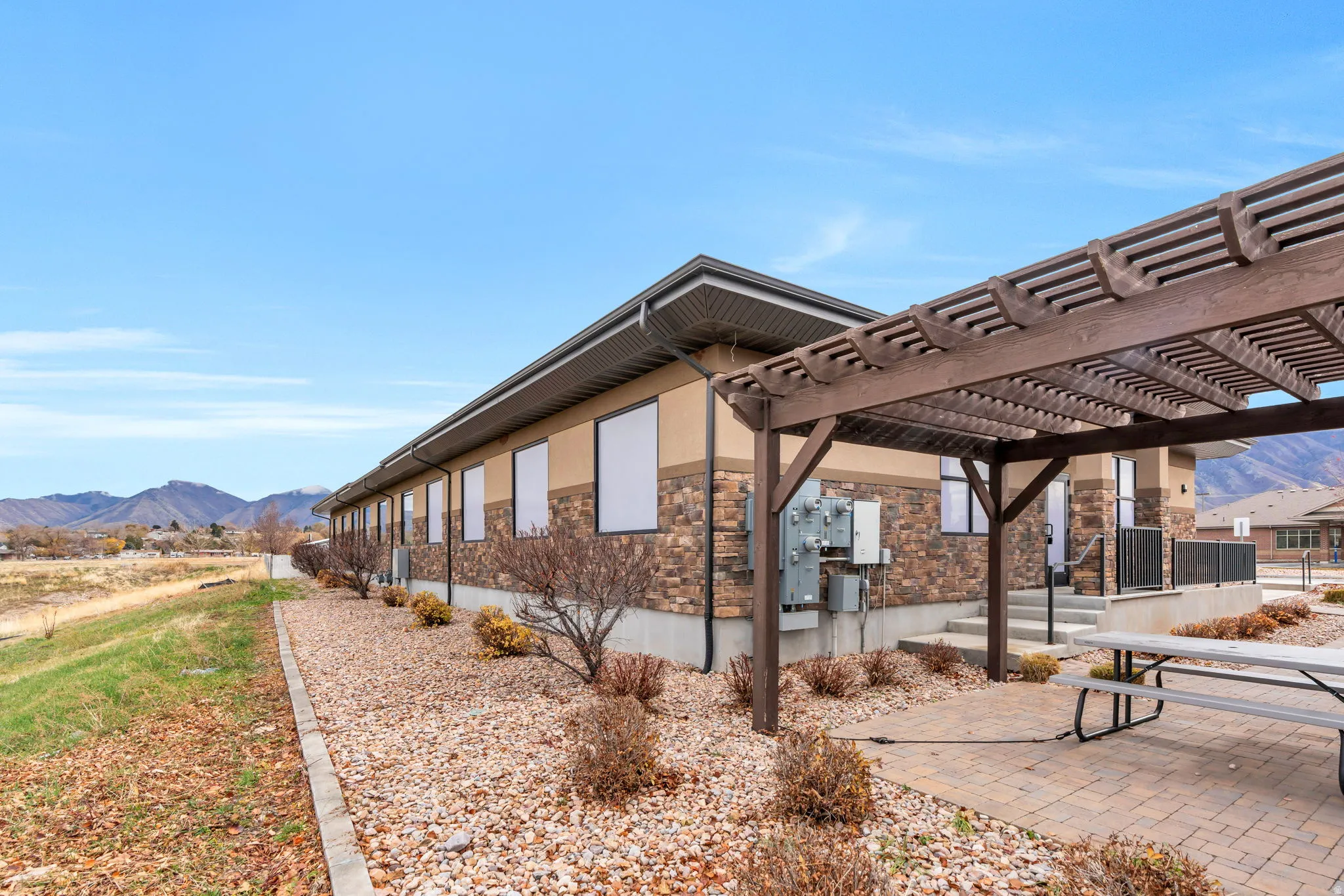 View of side of property featuring a mountain view, a pergola, a patio, and stone siding