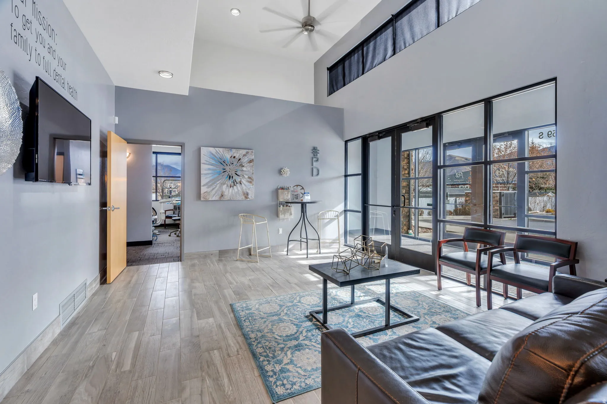Living area with plenty of natural light, wood finished floors, and a towering ceiling