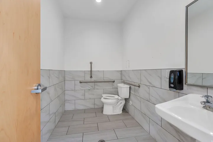 Half bath featuring tile walls, recessed lighting, light tile patterned flooring, and wainscoting