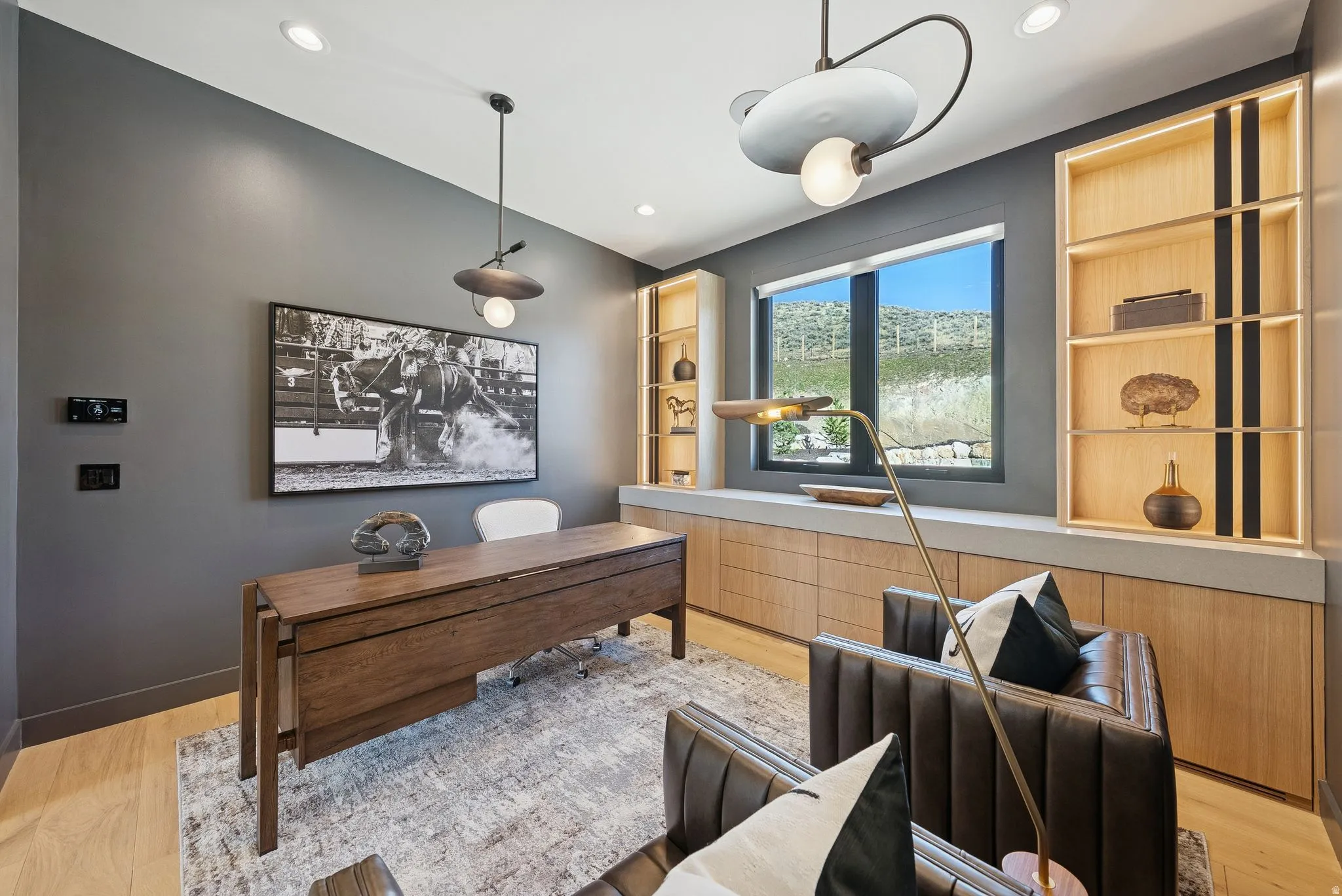 Home office with light wood finished floors and built in features