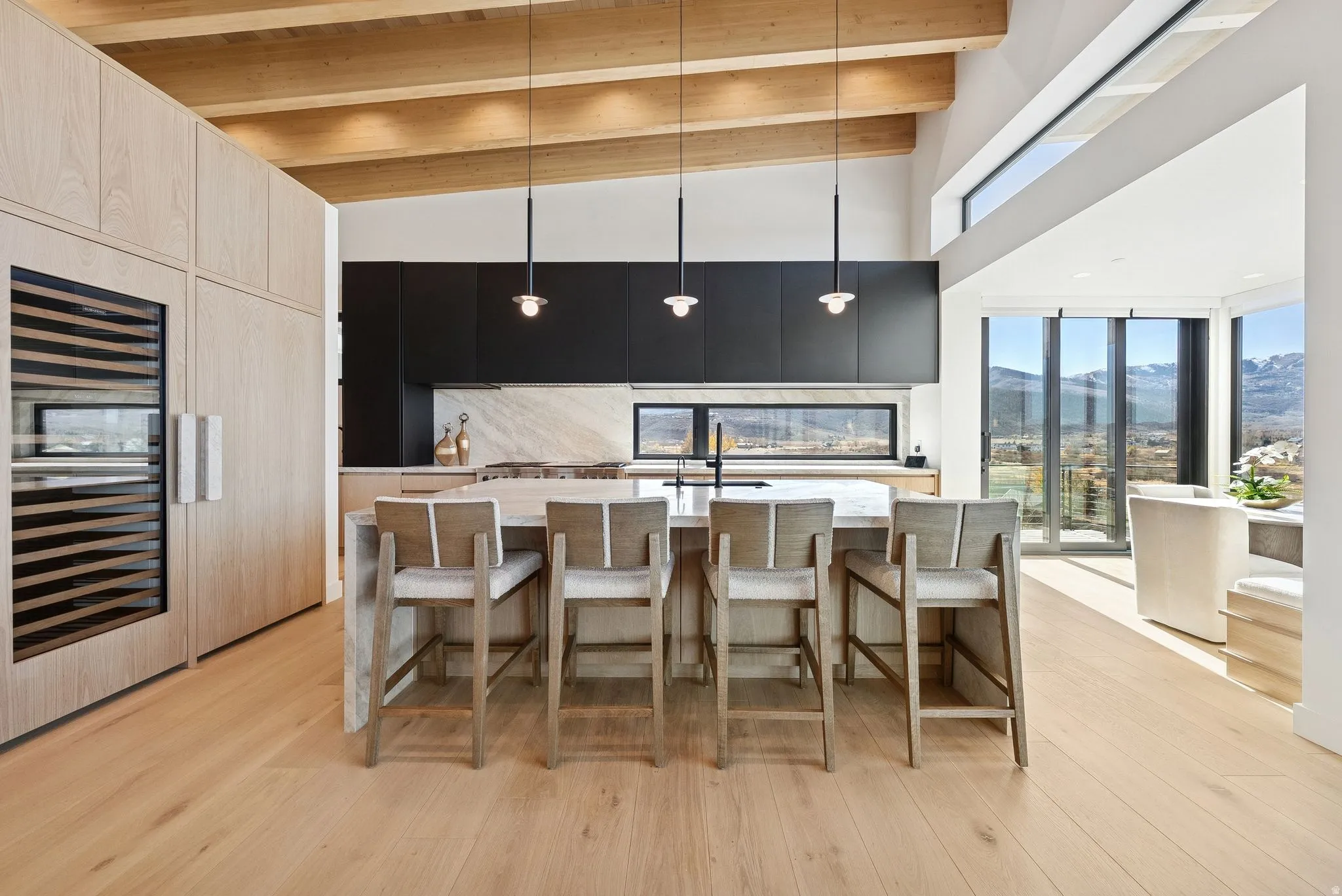 Kitchen with a mountain view, a breakfast bar area, decorative light fixtures, modern cabinets, and a kitchen island with sink