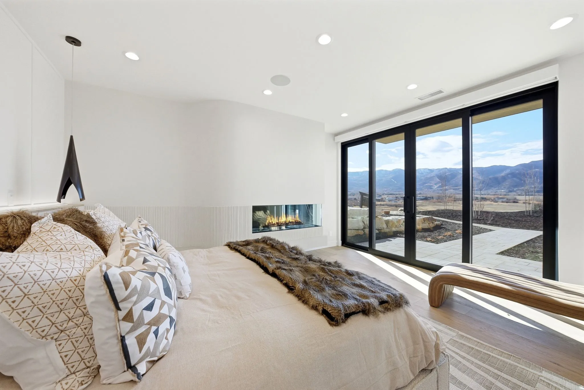 Bedroom with a mountain view, access to exterior, wood finished floors, recessed lighting, and a glass covered fireplace