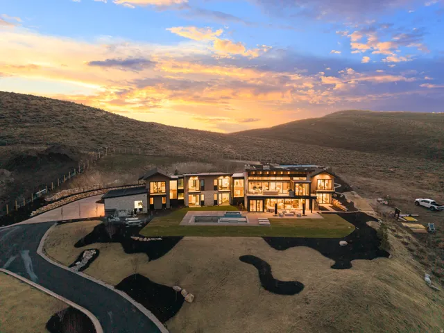 Contemporary architectural design featuring extensive glass window walls, multiple outdoor patio spaces, an in-ground swimming pool, and a winding paved driveway