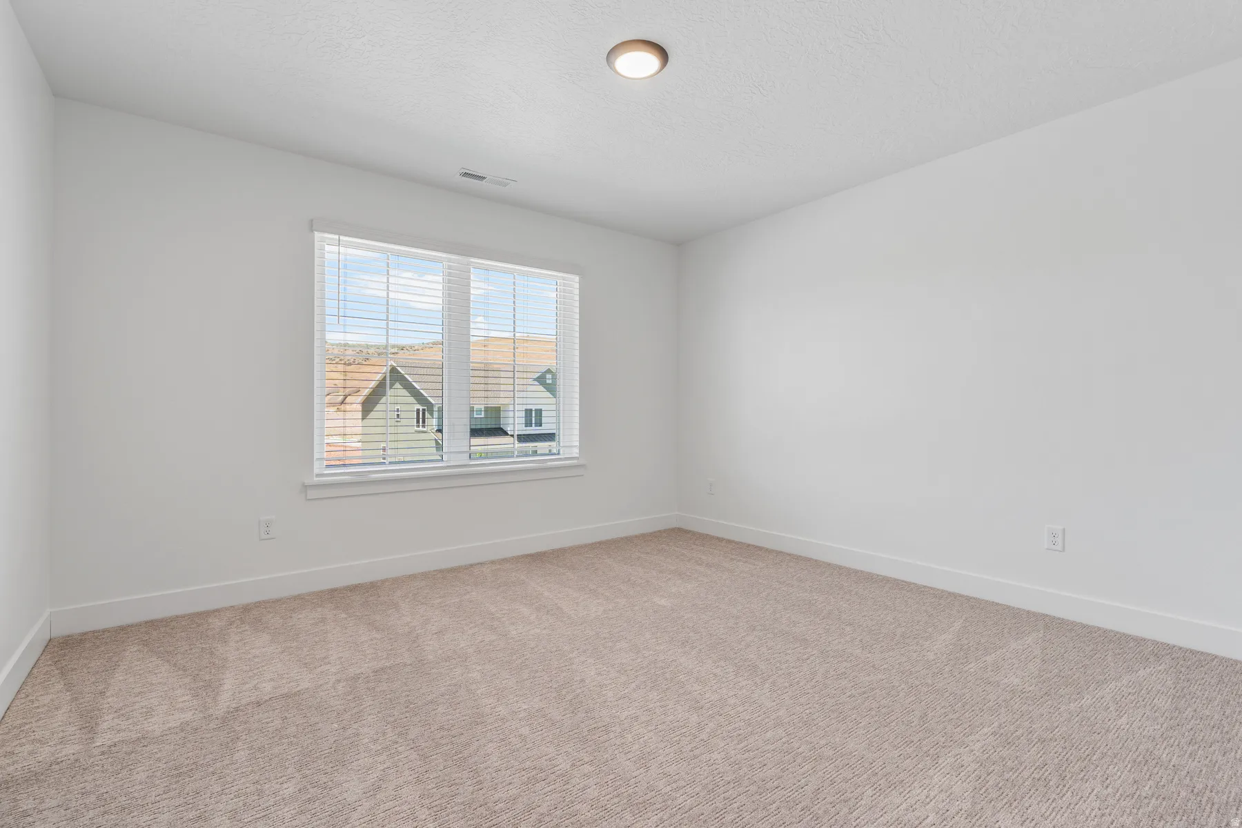 Empty room with light carpet and a textured ceiling
