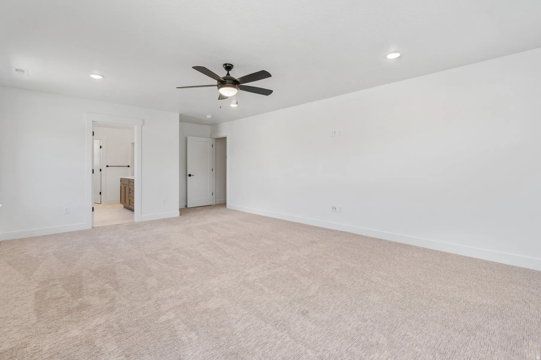 Unfurnished bedroom with light carpet, ceiling fan, recessed lighting, and ensuite bathroom