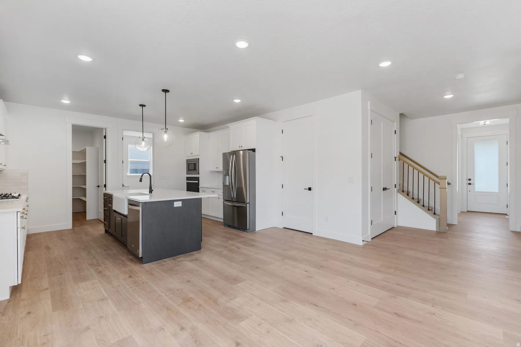 Kitchen with white cabinets, hanging light fixtures, light wood-style floors, recessed lighting, and stainless steel appliances