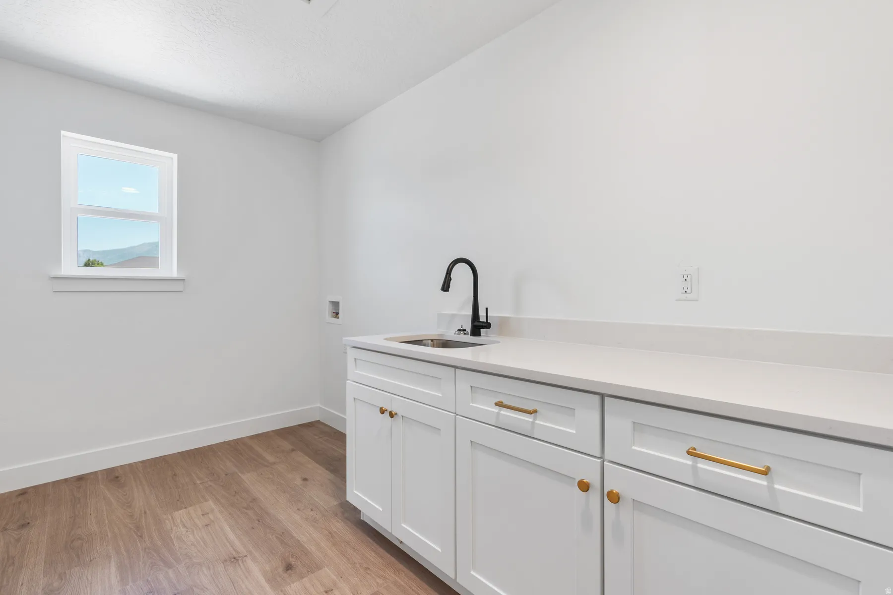 Laundry room with washer hookup, light wood-type flooring, cabinet space, and a textured ceiling